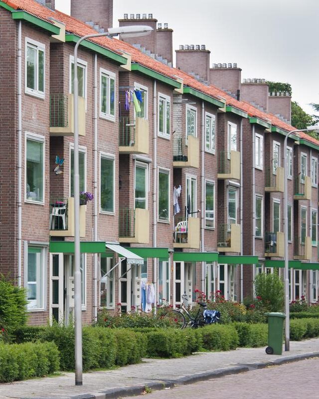 Rij appartementen met groene accenten, passend bij verzekeringen voor VvE's.