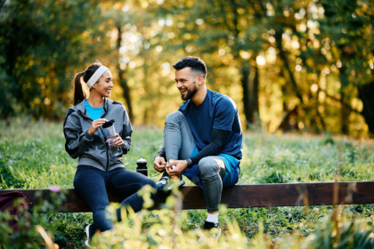 Jong stel in sportkleding rust uit in het park na een workout, in gesprek over hun financiële toekomst en pensioenbeleggen.