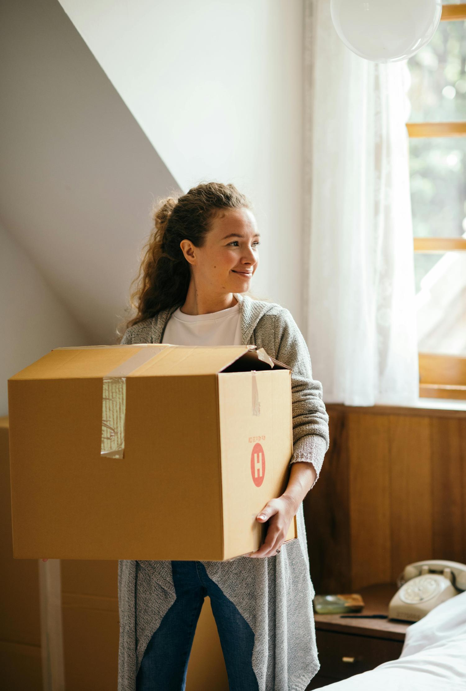 Jonge vrouw verhuist naar nieuwe woning dankzij hulp van garantstelling bij hypotheek.
