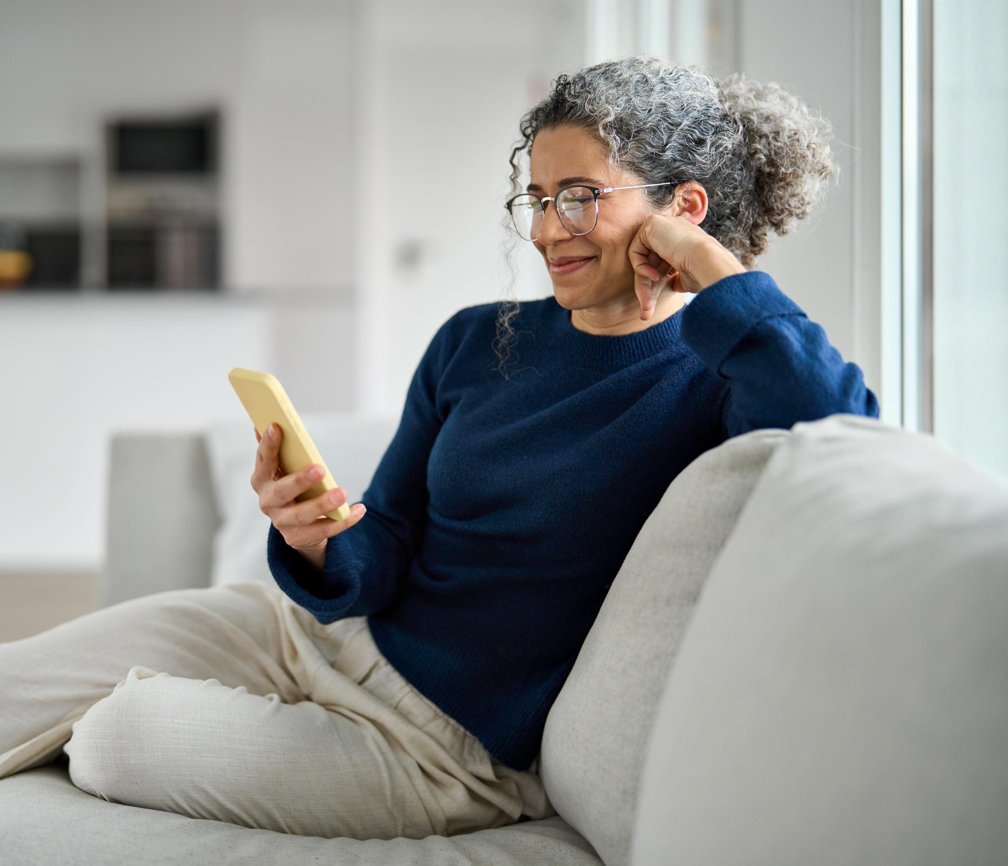 Vrouw leest op haar telefoon informatie over het afsluiten van een hypotheek met hulp van ouders.