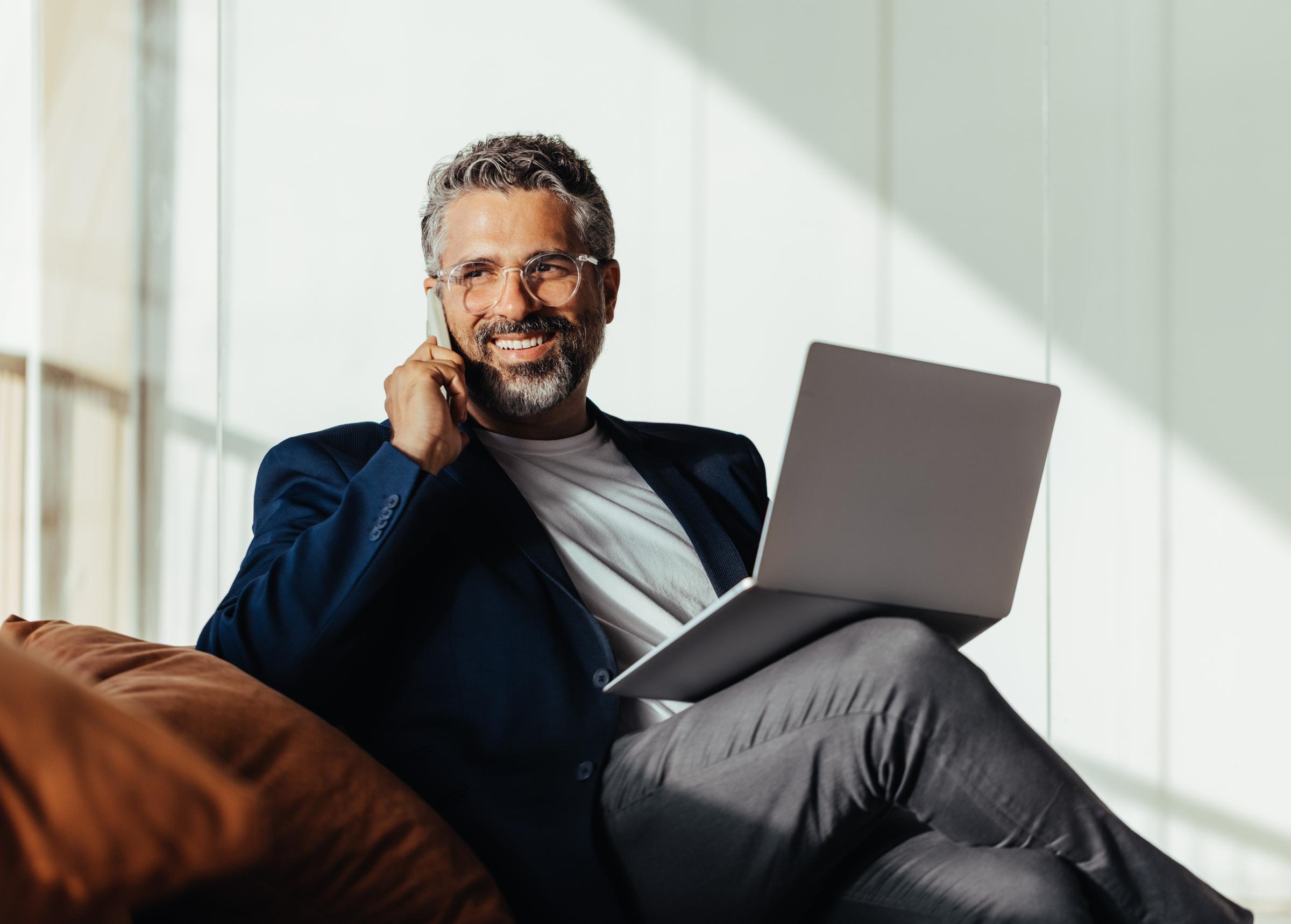 Man bespreekt voorwaarden van een familiehypotheek met adviseur van EVR via telefoon en laptop.