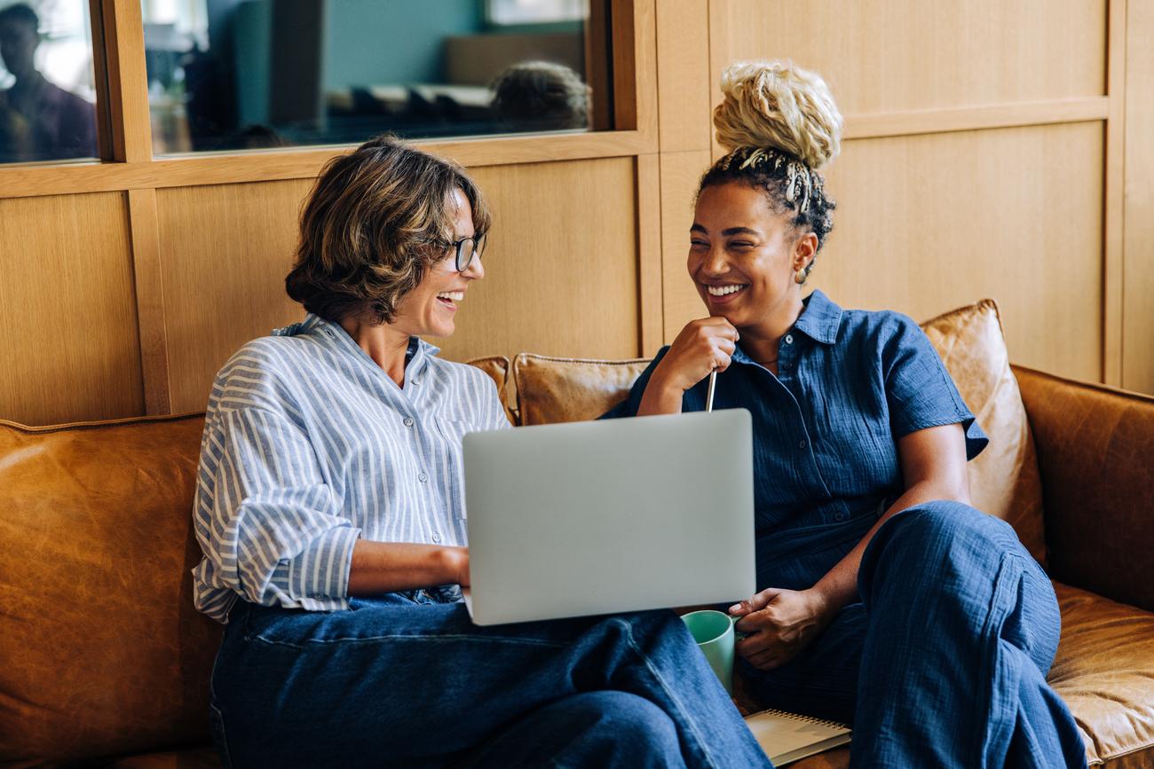 Twee vrouwen bespreken de Miljoenennota 2026 met laptop en koffie op de bank.