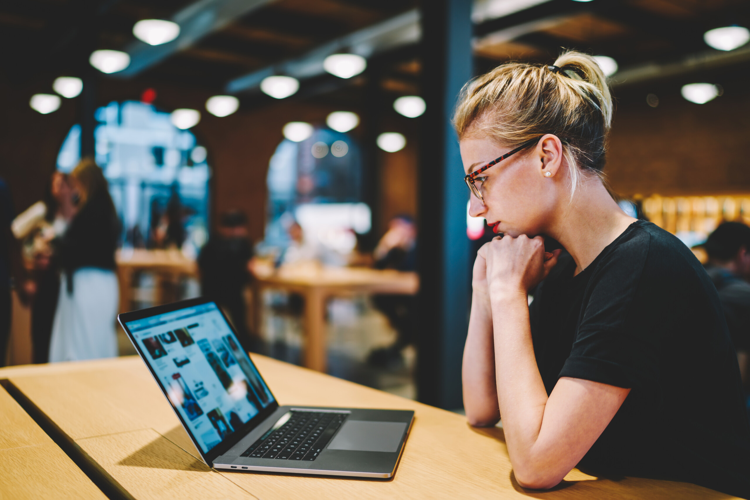 Vrouw kijkt geconcentreerd naar haar laptop in een moderne werkruimte, passend bij het thema Cybercrime treft Nederlanders, symbool voor online veiligheid en bewust internetgebruik.