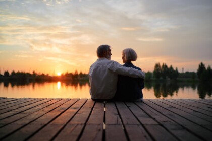 Echtpaar geniet van pensioen en AOW tijdens zonsondergang aan het water, passend bij pensioenadvies Zuid-holland.