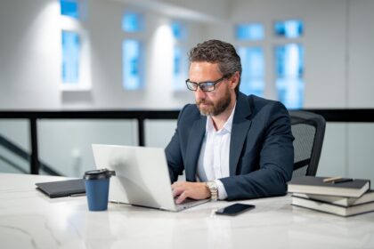 Man werkt op laptop op kantoor in het donker, passend bij mkb en digitale risico’s zoals datalekken.