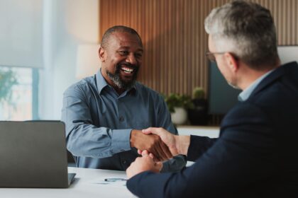 Werkgever en medewerker schudden elkaar de hand tijdens een gesprek over verzuimbeleid en duurzame inzetbaarheid op kantoor.
